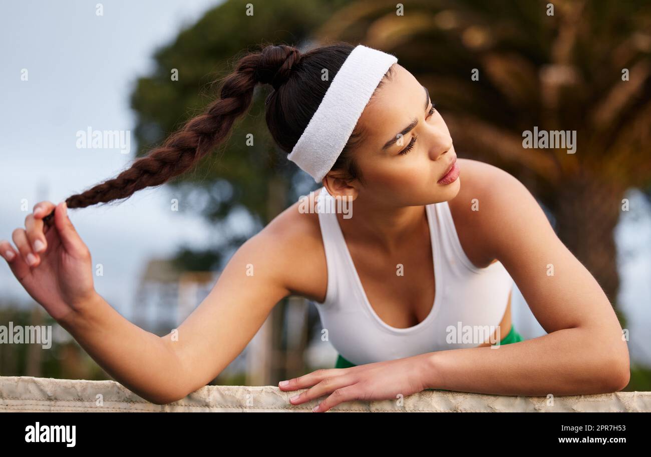 Je rejoue mon match encore et encore dans mes cheveux. Une jeune femme sportive penchée sur le filet de tennis. Banque D'Images