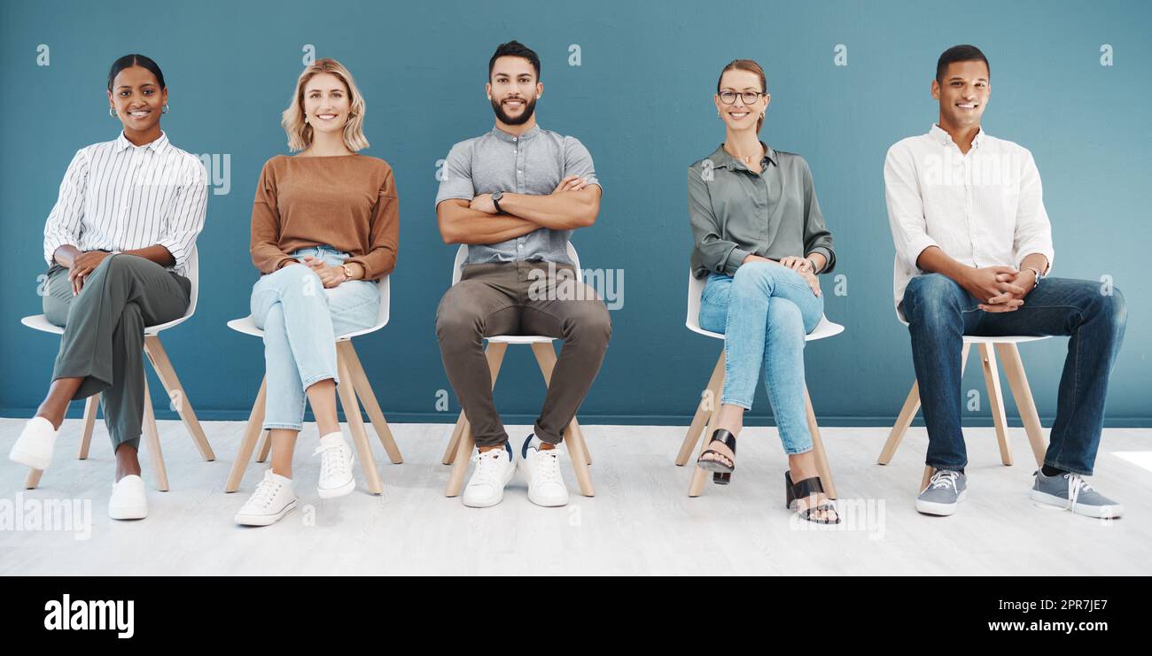 Portrait d'un groupe diversifié d'hommes et de femmes d'affaires confiants assis sur des chaises dans la salle d'attente sur un fond bleu. Les candidats et les candidats heureux et prometteurs sont prêts pour une entrevue de sélection en ligne pour une offre d'emploi et un poste vacant Banque D'Images