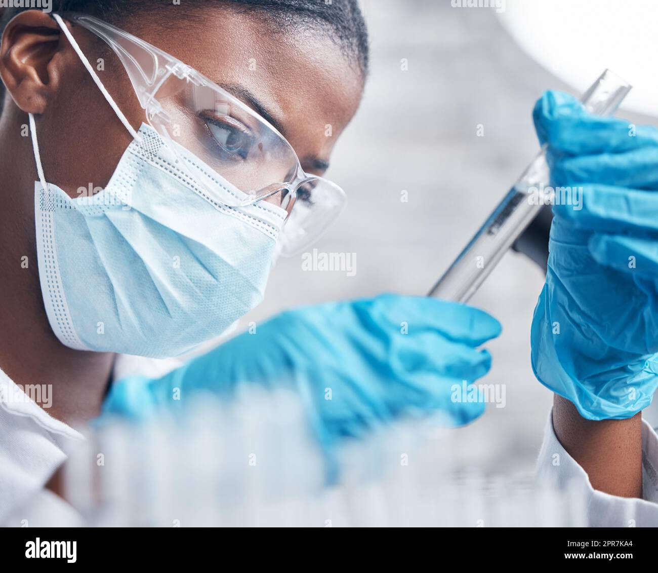 Scruter l'échantillon à portée de main. Un jeune scientifique travaillant avec des tubes à essai dans un laboratoire. Banque D'Images