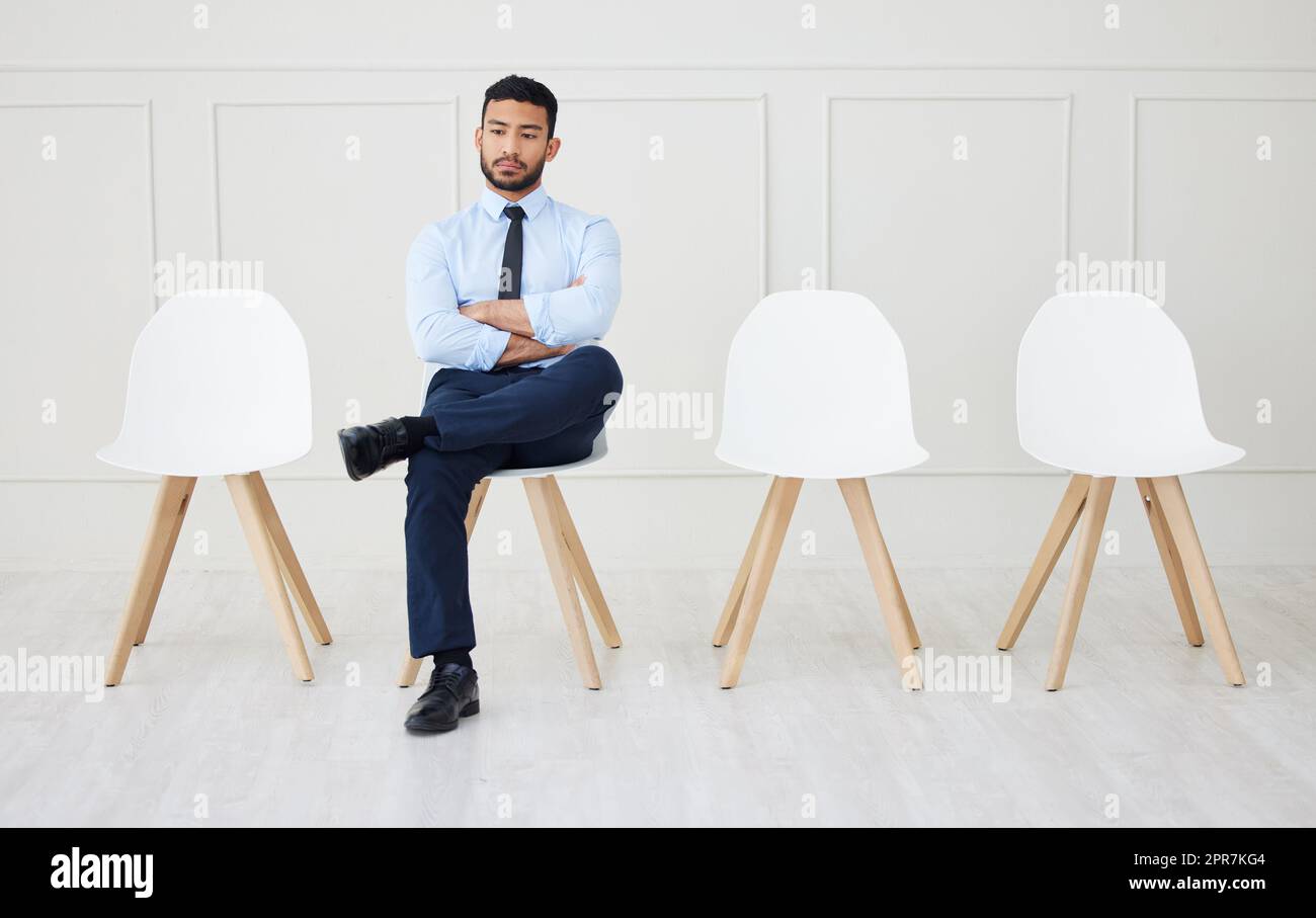 Pleine longueur d'homme d'affaires asiatique attendant une entrevue. Un jeune requérant impatient assis seul. Professionnel ethnique avec les armes pliées en ligne pour l'ouverture d'emploi, le poste vacant et l'occasion en fonction Banque D'Images