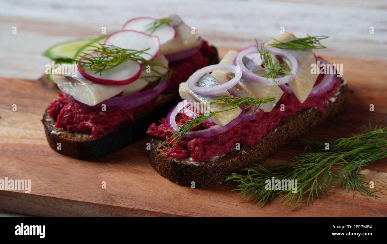 Sandwich ouvert danois Smorrebrod sur du pain de seigle noir avec du hareng, du saumon, de la betterave, des oignons rouges et du radis Banque D'Images