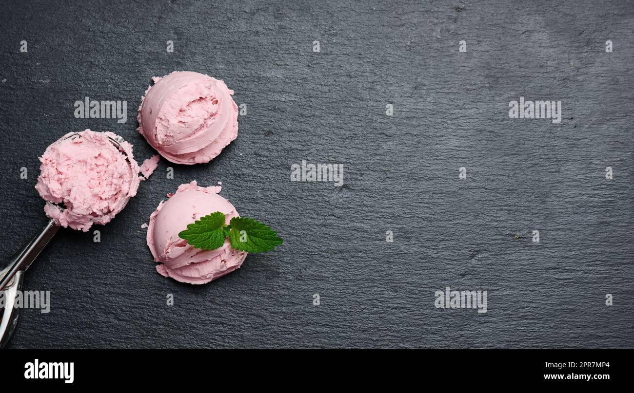 Boules de glace roses sur un panneau en pierre noire, vue du dessus Banque D'Images