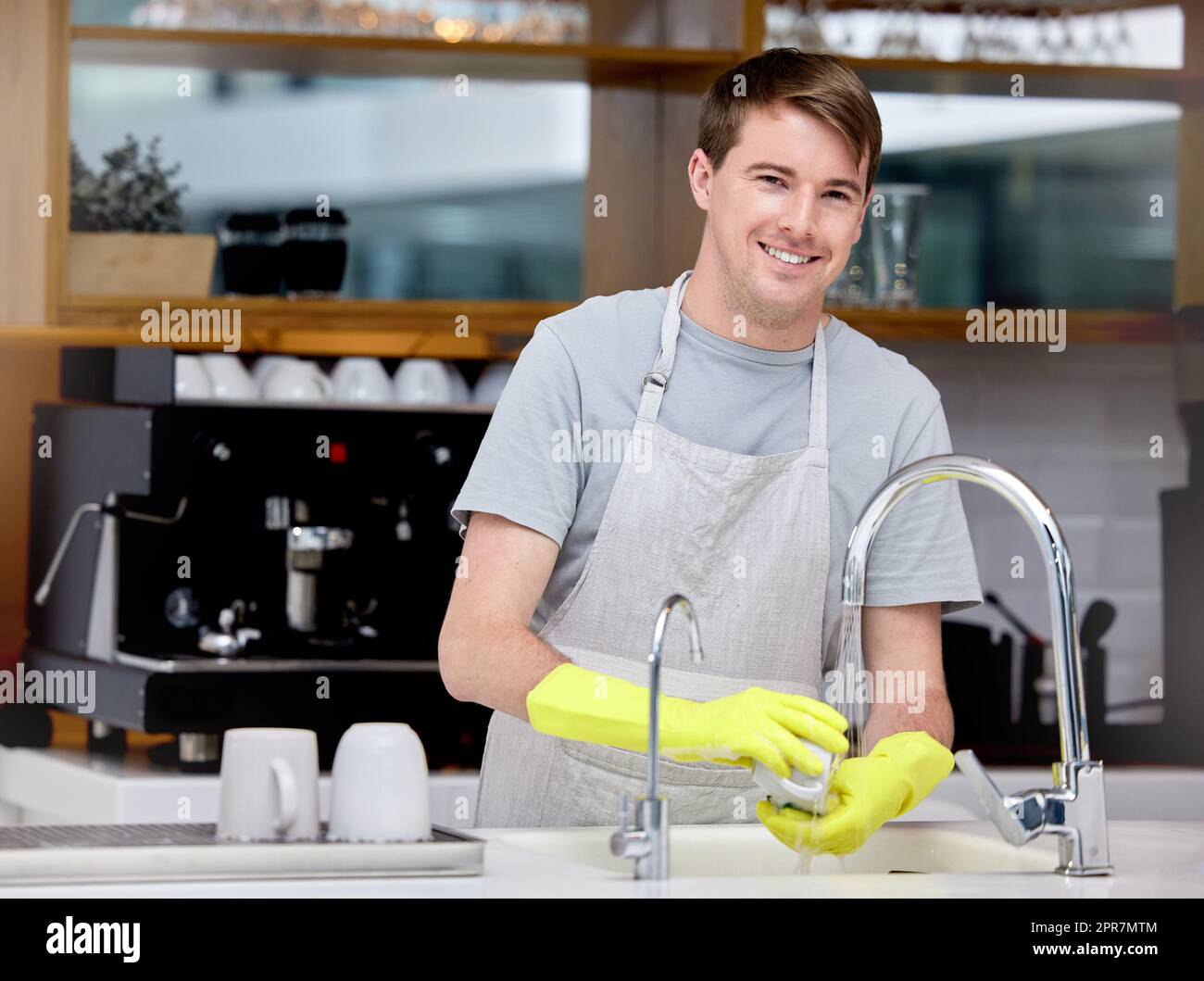 Faites-le étincelant propre. Un jeune homme lave des plats dans sa cuisine. Banque D'Images