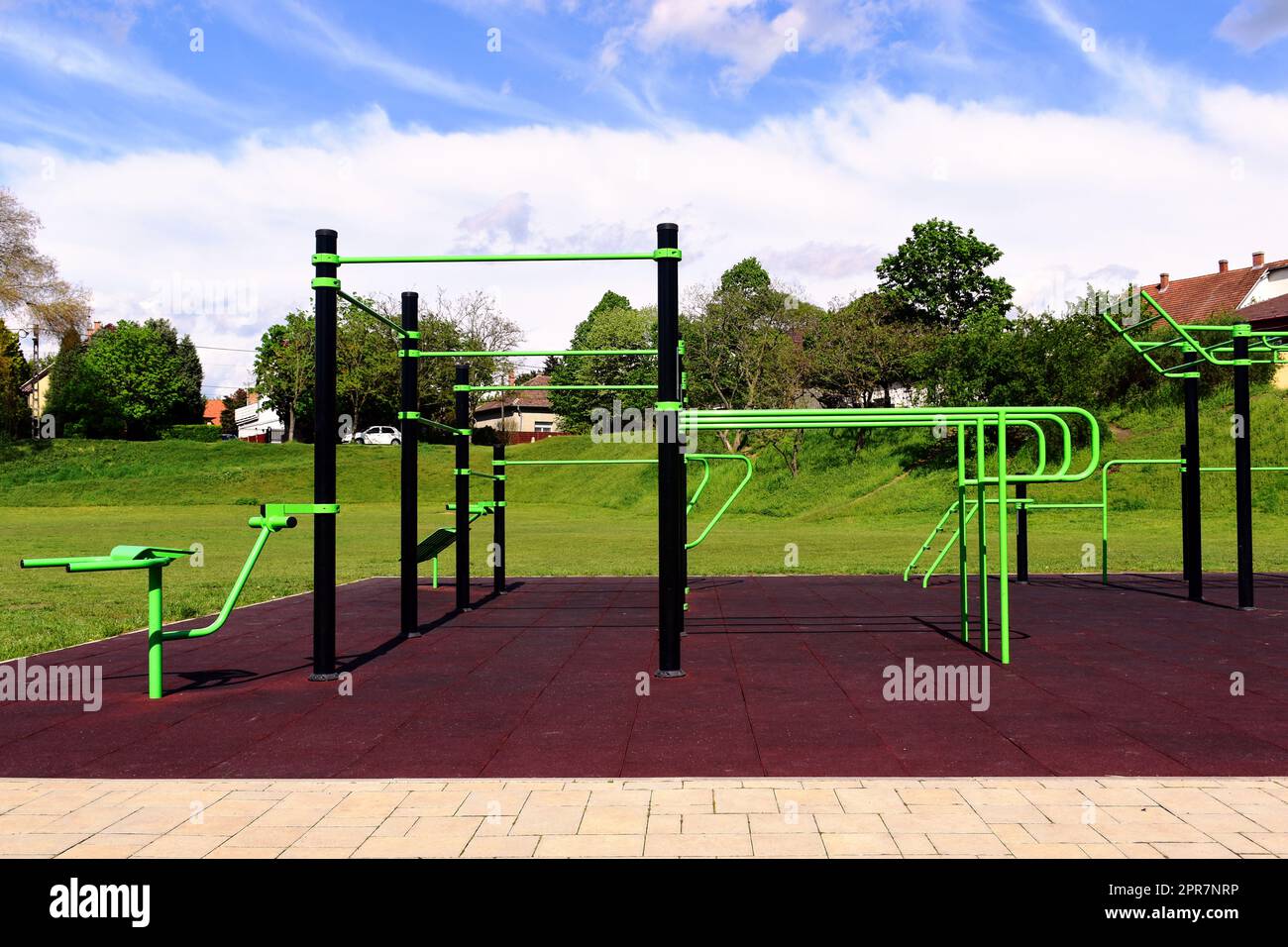 aire d'entraînement publique extérieure et parc sportif. équipement d'étirage et d'entraînement vert.sol de sécurité en caoutchouc doux rouge. barres d'escalade et brancard vert vif Banque D'Images