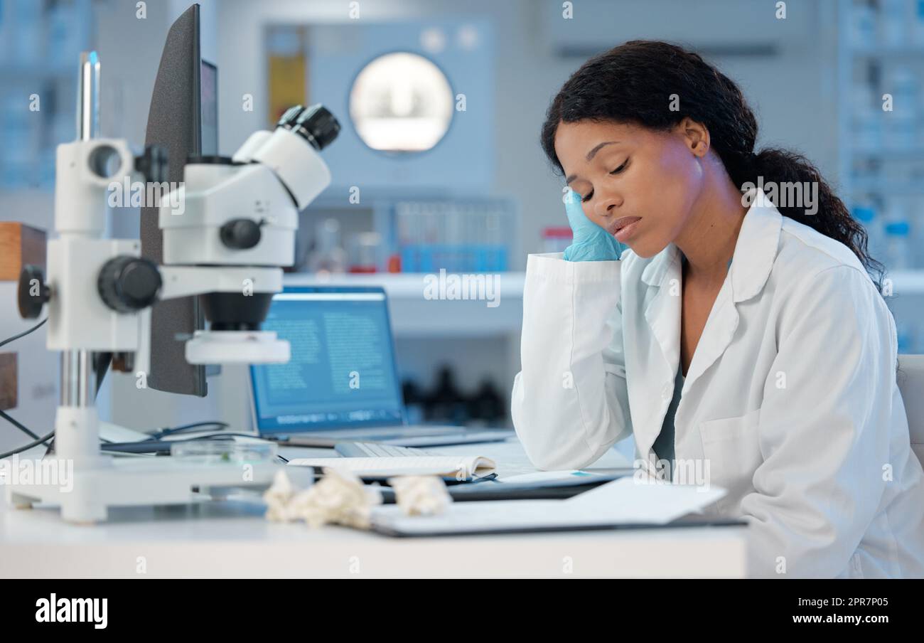 Compte à rebours des heures. Photo d'une jeune femme qui regarde s'ennuyer pendant qu'elle travaille dans son laboratoire. Banque D'Images
