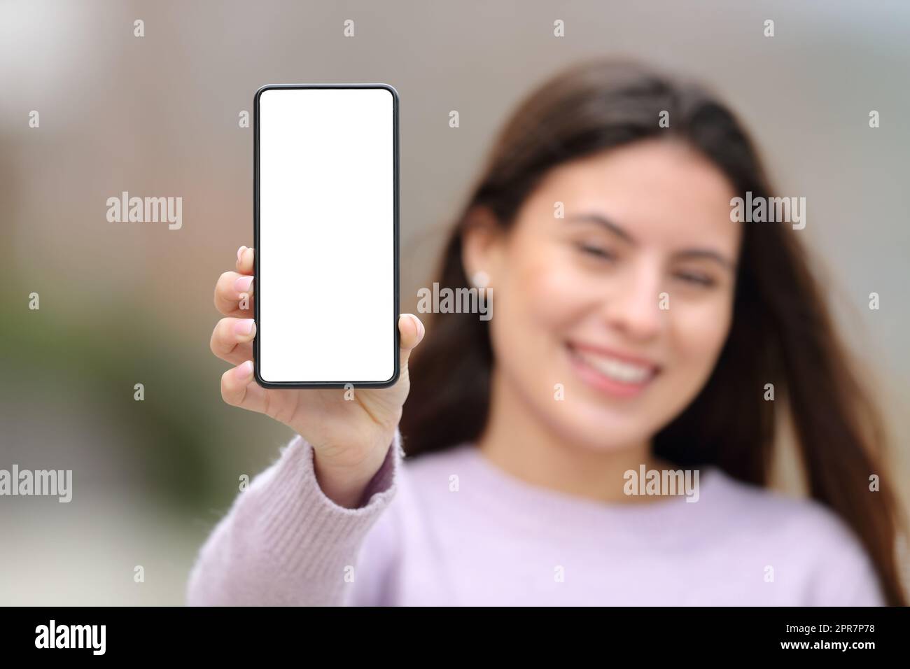 Bonne adolescente montrant un écran de téléphone cellulaire vierge Banque D'Images
