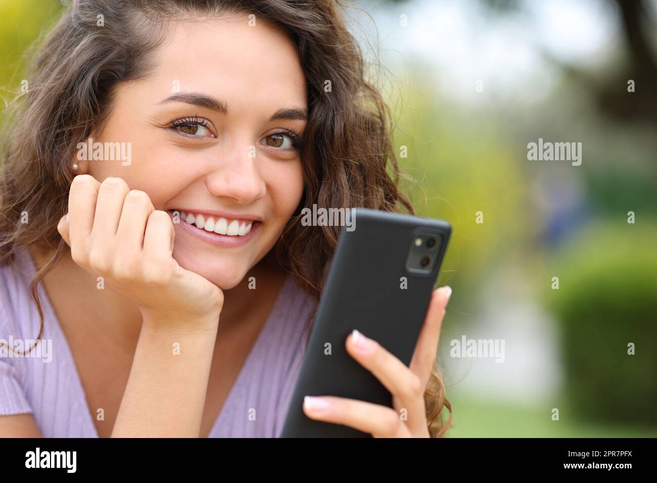 Une femme heureuse tenant un téléphone portable vous regarde Banque D'Images