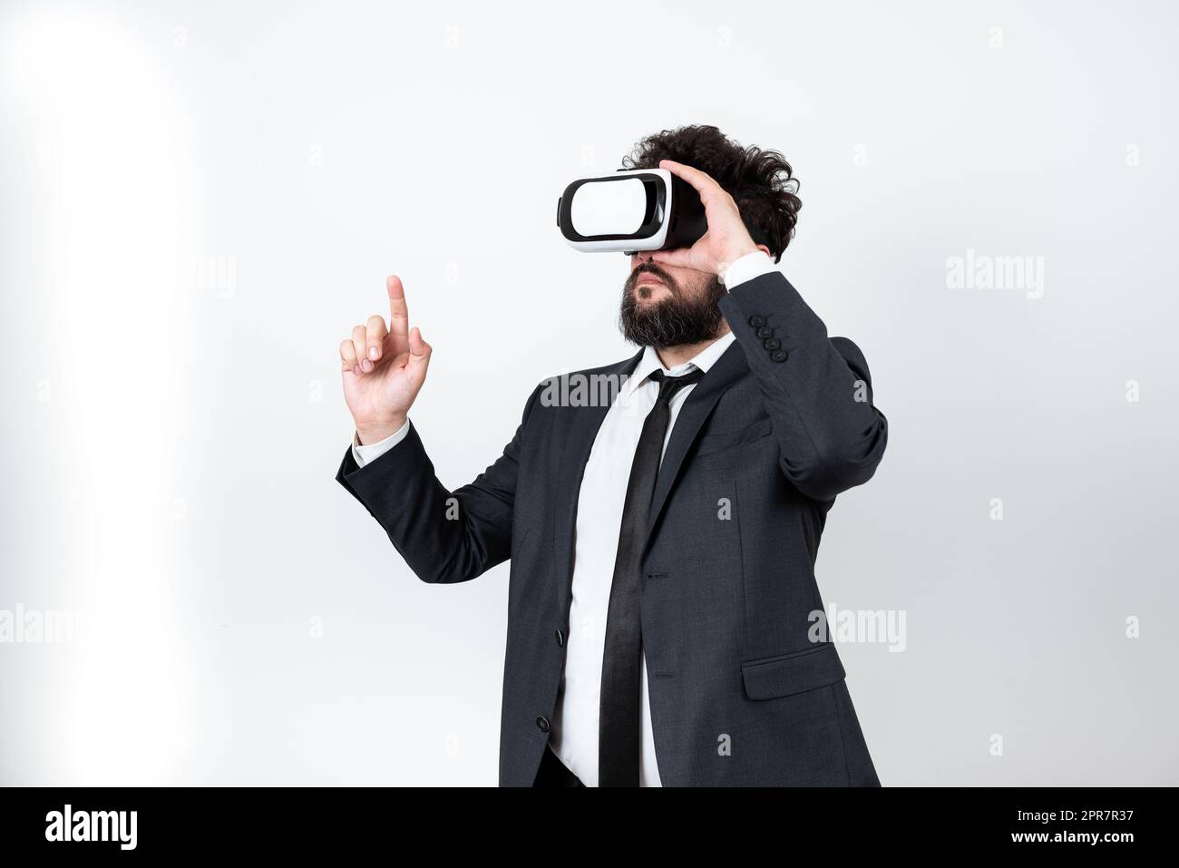 Homme portant des lunettes VR et pointant d'un doigt sur des messages importants. Homme d'affaires ayant des lunettes de réalité virtuelle et montrant des informations crutiales. Banque D'Images