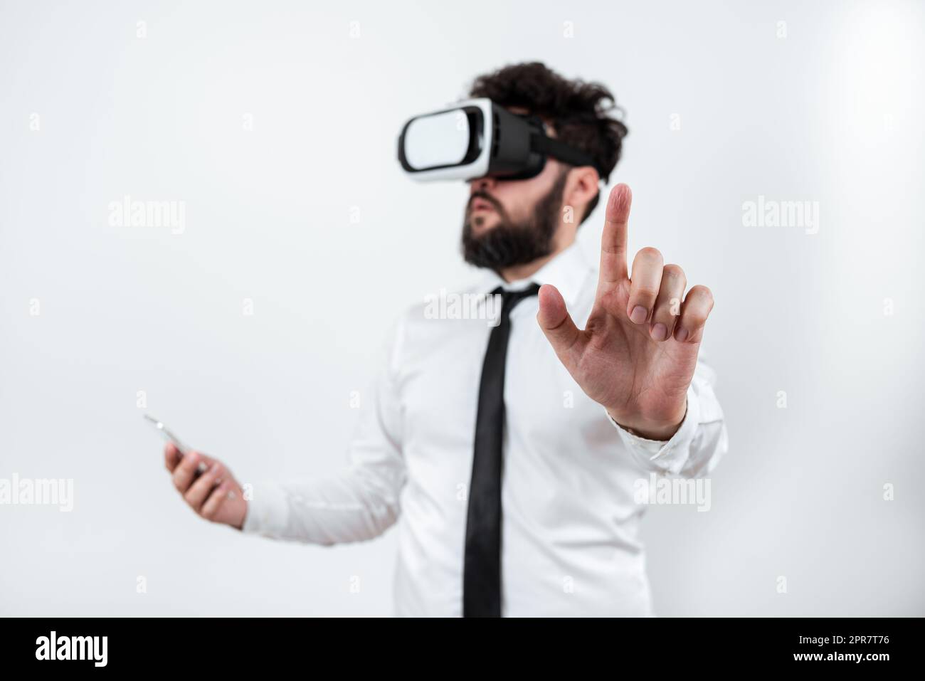 Homme tenant un téléphone portable, portant des lunettes VR et pointant d'un doigt sur les dernières mises à jour. Homme d'affaires ayant des lunettes de réalité virtuelle, le téléphone portable et la présentation de Nouvelle idée. Banque D'Images