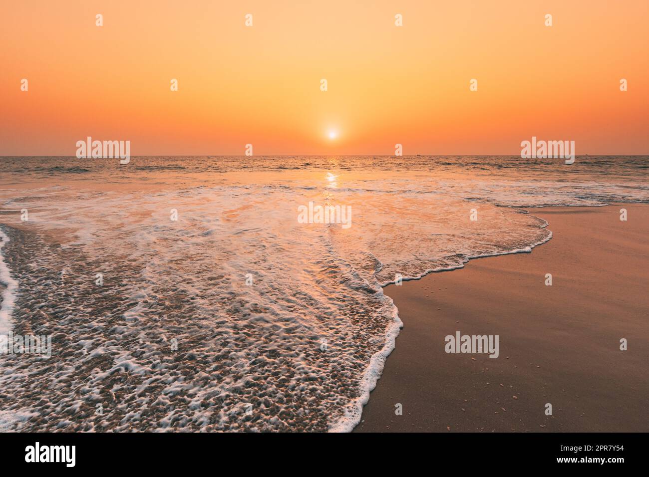 Coucher de soleil au-dessus de la mer. Ciel lever de soleil naturel couleurs chaudes sur la mer Ripple. Eau de mer mousse lavage Sandy Beach au coucher du soleil Banque D'Images