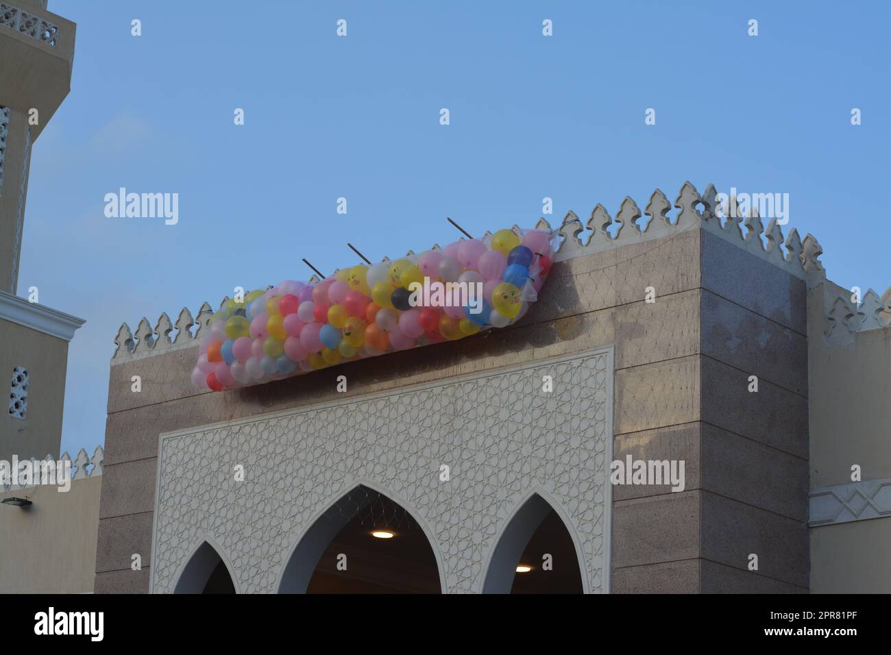 Contexte de fête et de célébrations à l'extérieur d'une mosquée au Caire Egypte avec des dizaines de ballons tenus dans le toit de la mosquée à côté du minaret à jeter Banque D'Images