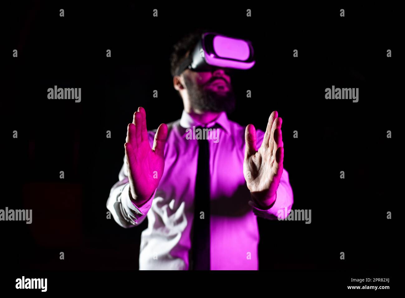 Homme d'affaires barbu portant des lunettes de réalité virtuelle et appréciant Simulator. La lumière tombe sur l'homme à l'aide d'un gadget futuriste gestant et présentant une technologie innovante moderne. Banque D'Images