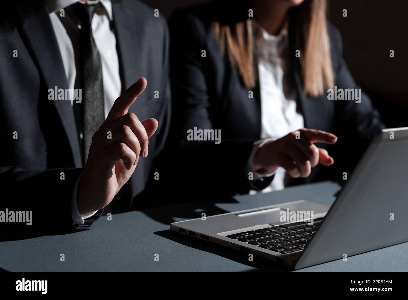 Homme et femme pointant avec les doigts sur les messages importants assis sur le bureau avec le recouvrement. L'équipe commerciale présente les informations les plus confidentielles avec les mains. Cadres montrant des données. Banque D'Images