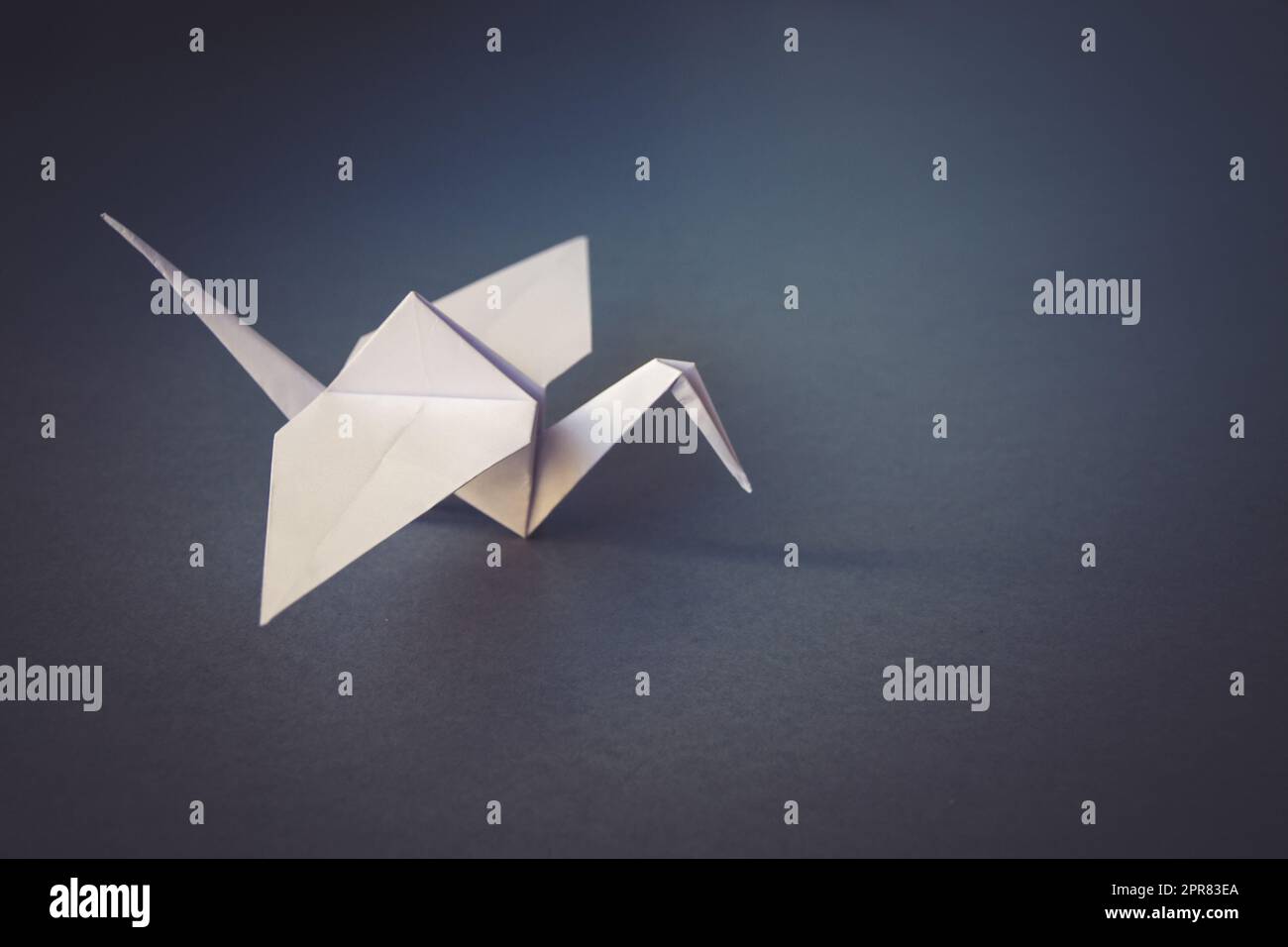 Grue à papier blanc origami isolé sur fond gris Banque D'Images