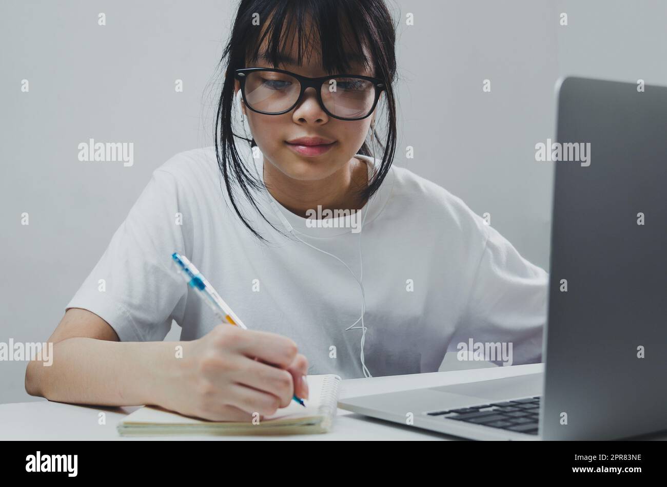 fille tenant stylo écriture livre étude d'apprentissage numérique internet vidéo en ligne ordinateur portable à la maison. Banque D'Images