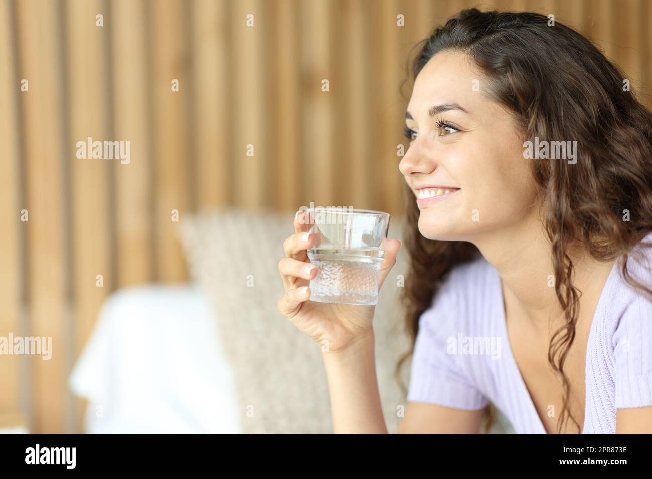 Bonne femme regardant loin tenant un verre d'eau Banque D'Images