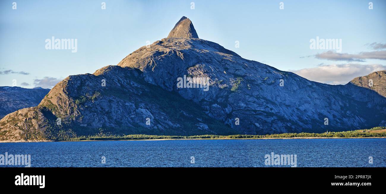 Vue panoramique une montagne bordant une côte à Bodo, Norvège. Une vue naturelle étendue d'un lac de source au lever du soleil le matin. Végétation luxuriante et isolée le long d'un lac dans une destination européenne Banque D'Images