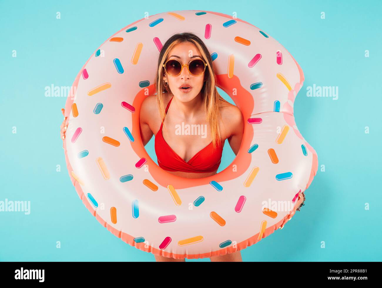 Une femme stupéfait sort d'un donut gonflable Banque D'Images