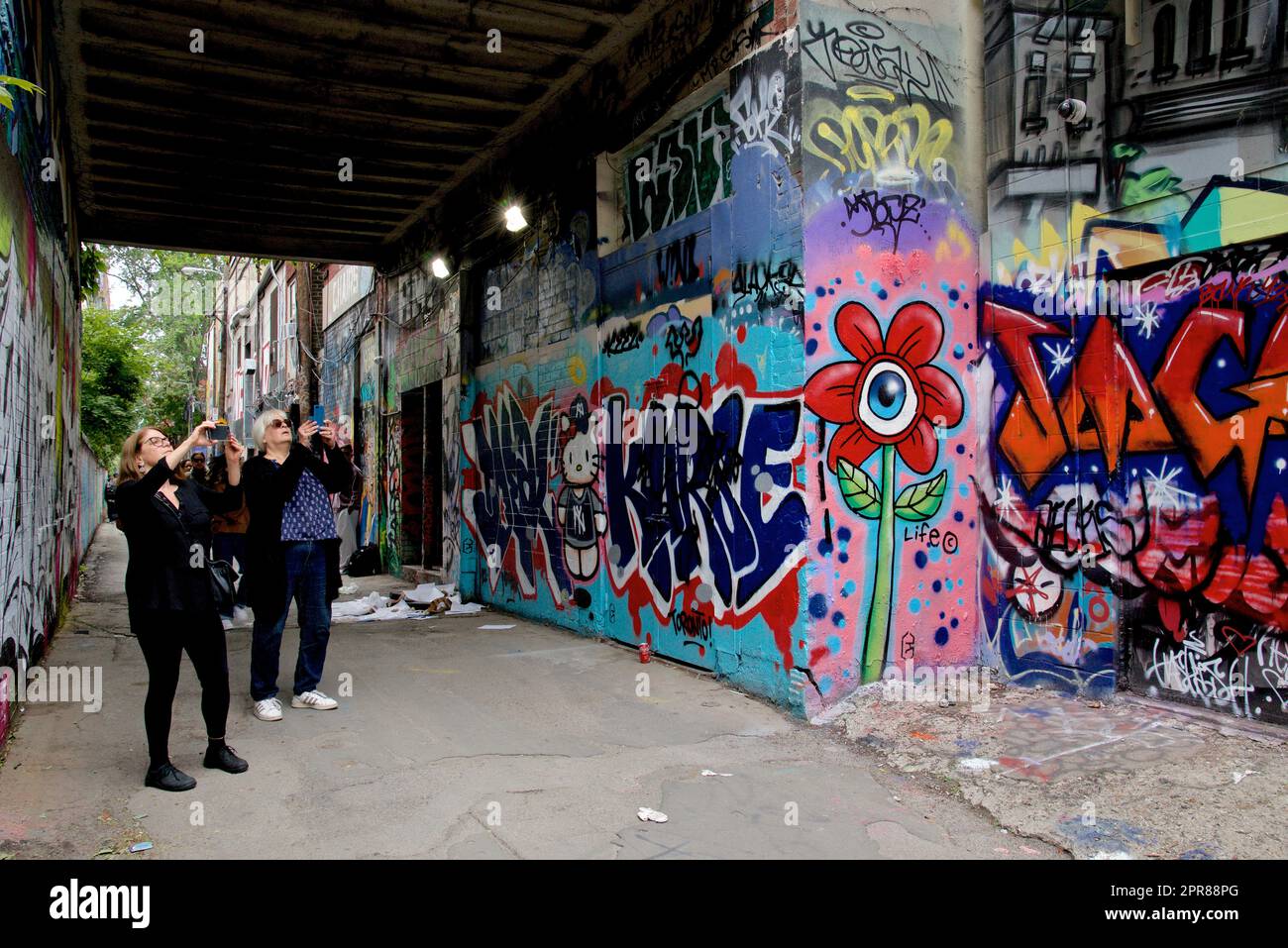 Toronto, Ontario / Canada - le 24 septembre 2022 : une femme prend une photo des graffitis colorés sur le mur dans une allée à Toronto, Ontario, Canada Banque D'Images