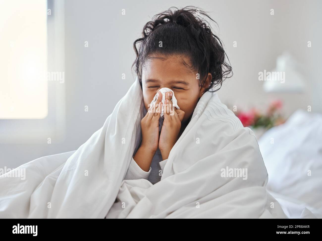 Cette période de l'année. Photo d'une petite fille qui soufflait le nez et qui a l'air malade au lit. Banque D'Images