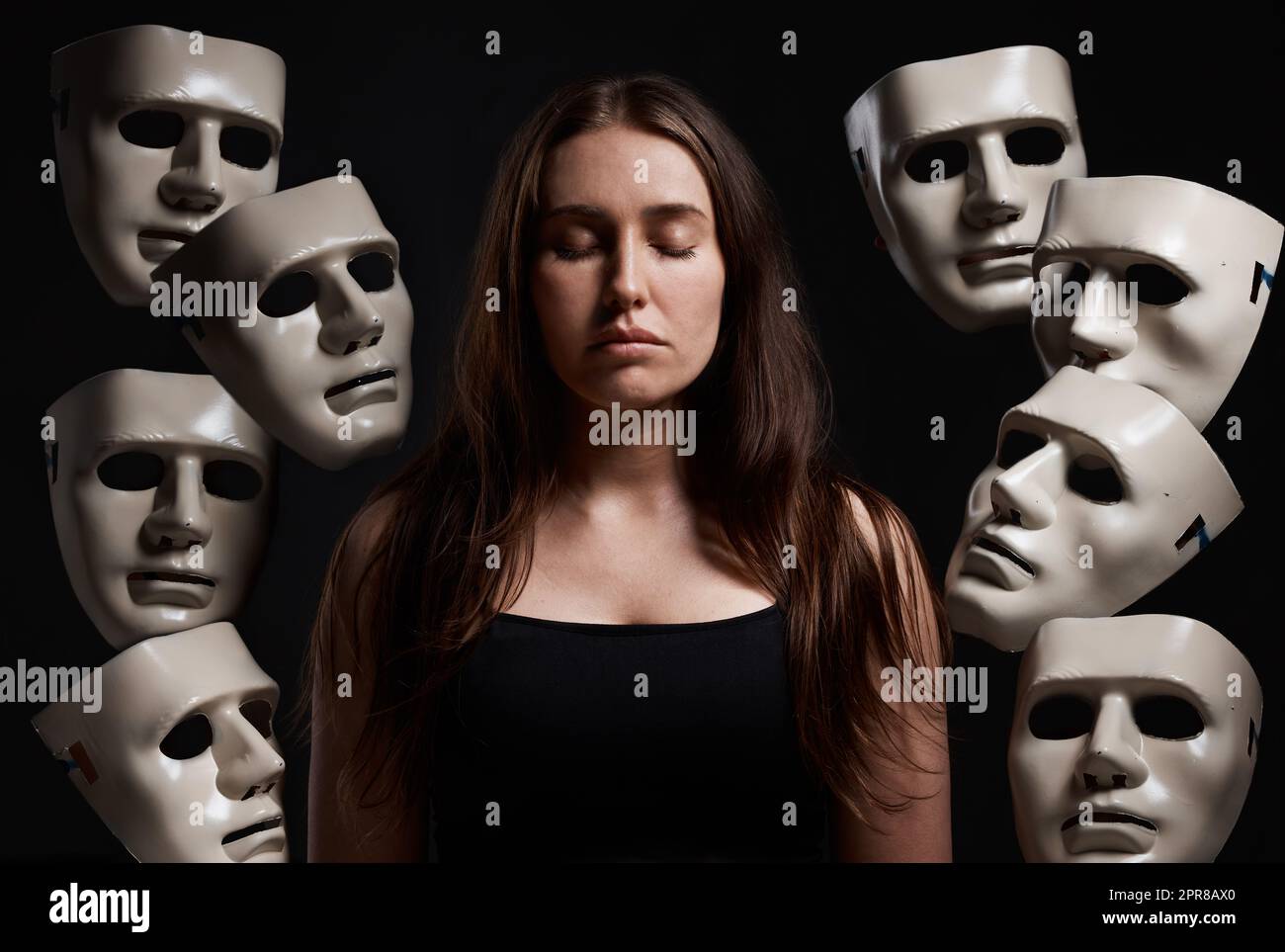 Je contrôle mes propres émotions. Studio photo d'une femme debout avec ses yeux fermés tout en étant entourée de masques. Banque D'Images