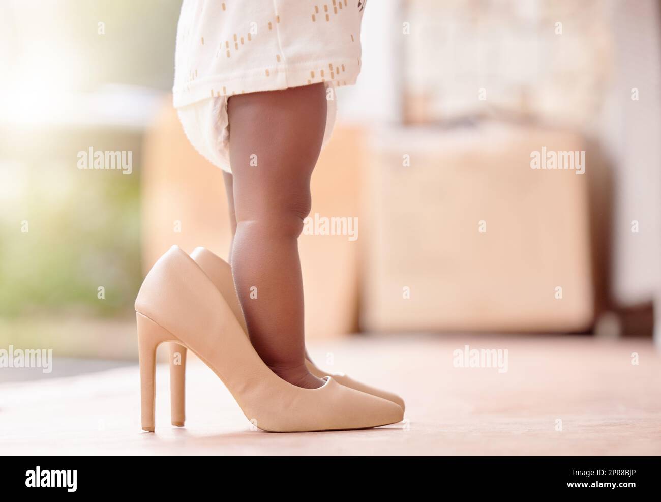 Un jour, vous hériterez de ces enfants. Une petite fille jouant robe avec ses mères talons hauts. Banque D'Images