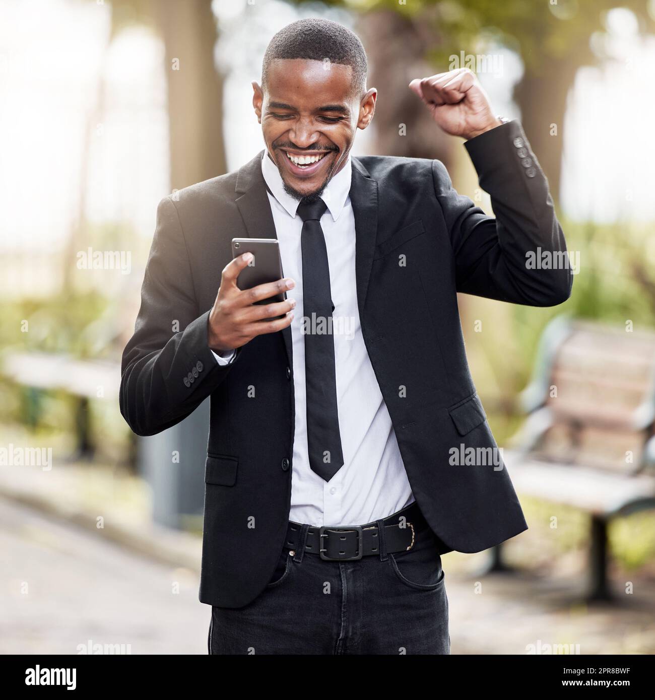 Oui, j'ai eu le travail. Un beau jeune homme d'affaires qui applaudit à son téléphone portable pendant son trajet du matin au travail. Banque D'Images