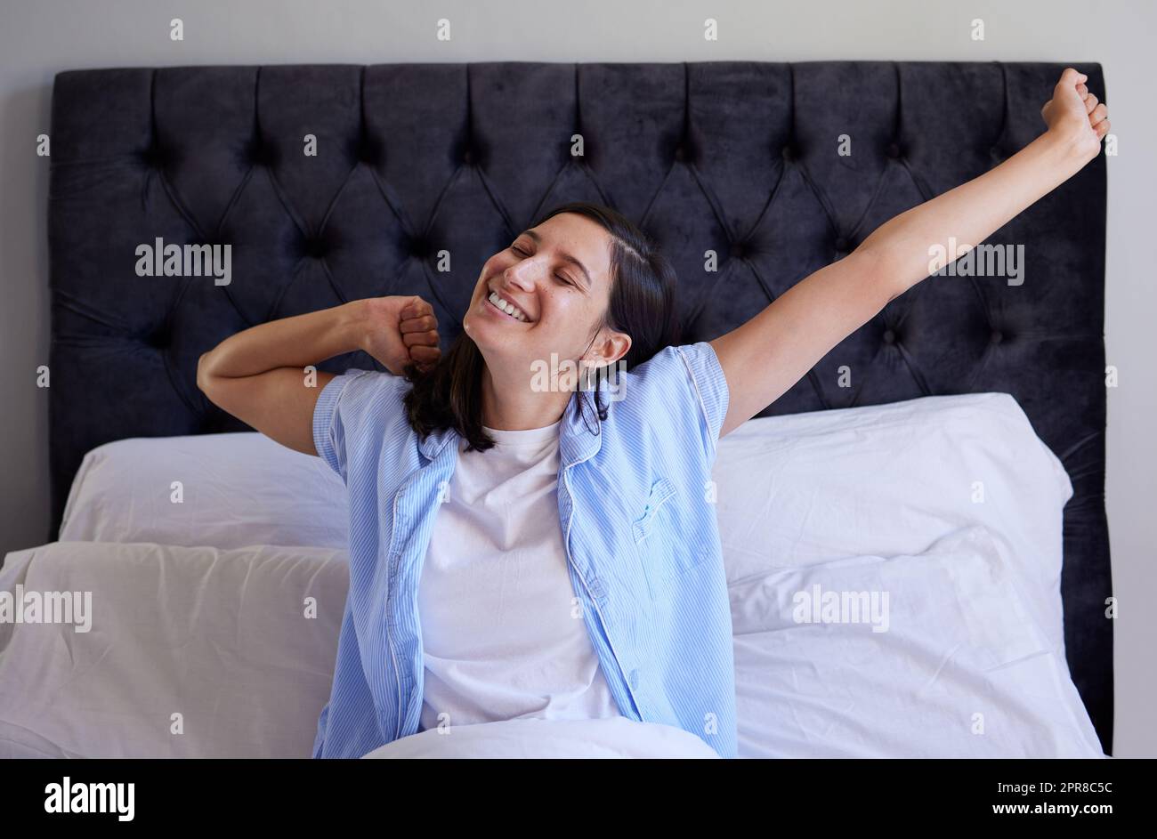 Elle se lève pour saisir le jour. Jeune femme se réveillant de son sommeil dans son lit à la maison. Banque D'Images