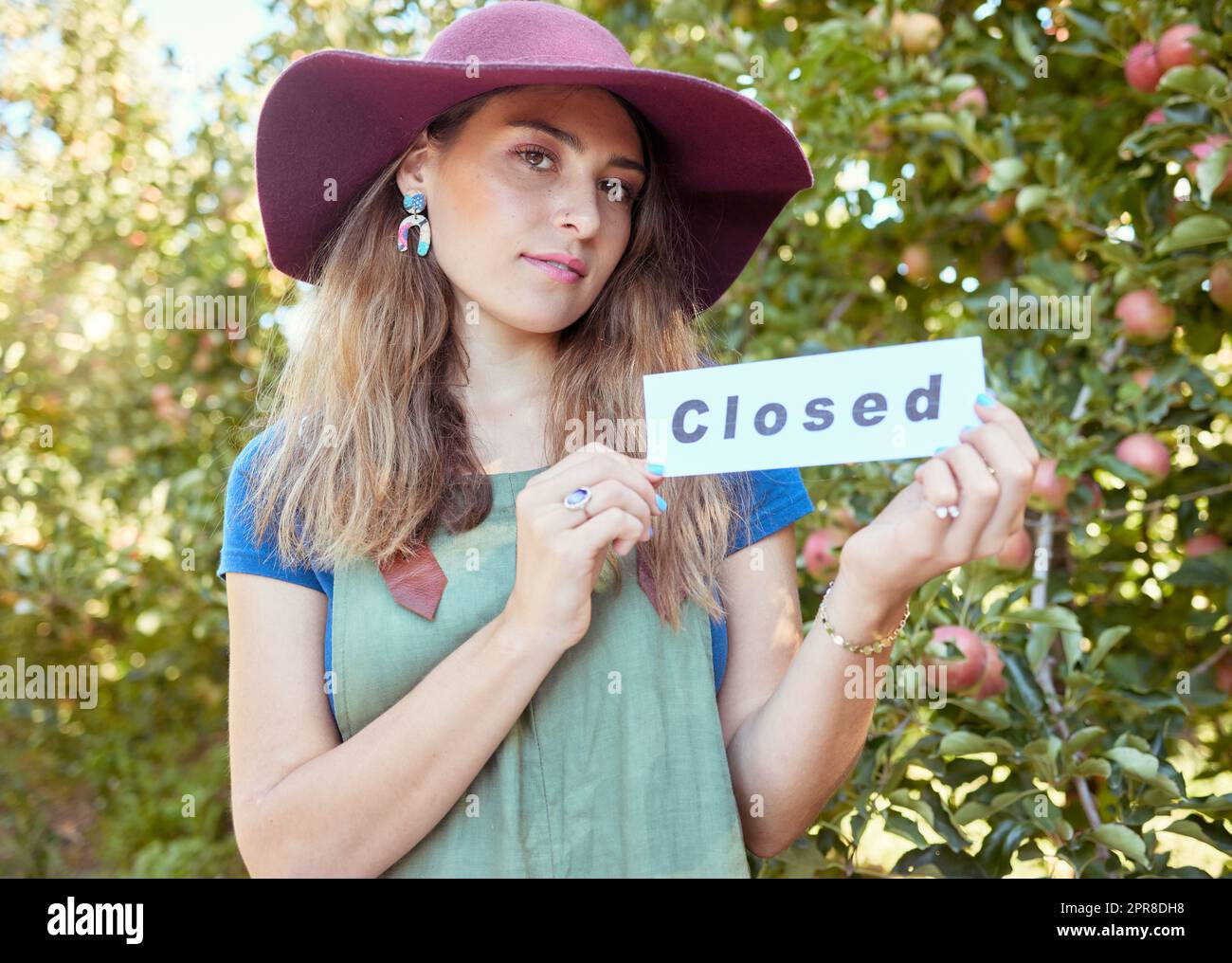 Portrait d'une femme tenant un panneau fermé pour annoncer la fin de la saison de cueillette des pommes sur une ferme de vergers. Les agriculteurs ferment leurs activités agricoles en raison de la faillite, de la récession, de la pandémie et de la faillite de l'économie Banque D'Images