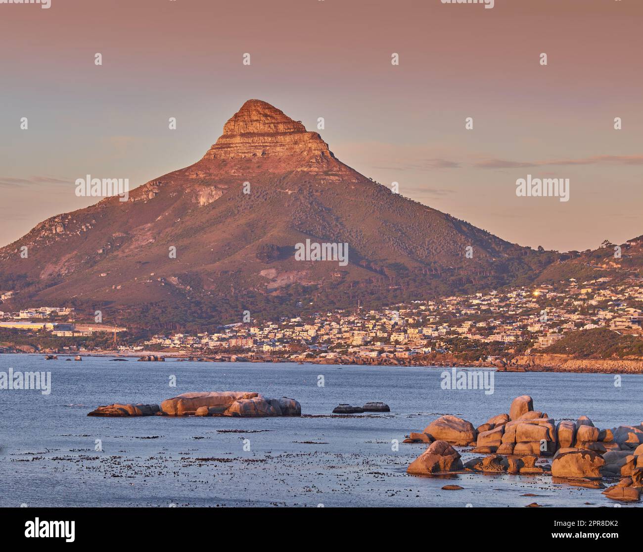 Copiez l'espace avec une vue panoramique sur le paysage d'une ville côtière le long de la montagne de Lions Head au Cap, en Afrique du Sud, sur un fond de ciel crépuscule. Vue panoramique sur la mer avec un point de repère emblématique au coucher du soleil Banque D'Images