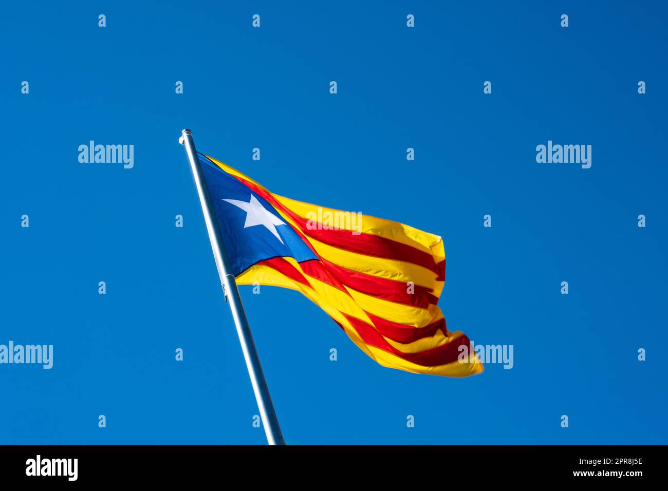 Le drapeau catalan Senyera ESTELADA agité isolé sur le ciel bleu. Mât incliné vers la gauche. Banque D'Images Le drapeau catalan Senyera ESTELADA agité isolé sur le ciel bleu. Mât incliné vers la gauche. Banque D'Images