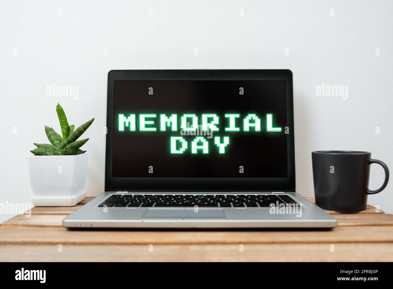 Légende conceptuelle Memorial Day. Mot pour honorer et rappeler ceux qui sont morts en service militaire Lap Top avec des informations importantes sur la table avec la plante et la tasse de café. Banque D'Images