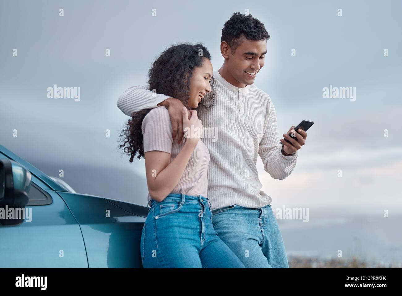 Voyons ce que les médias sociaux ont à dire. Photo d'un jeune couple en utilisant un téléphone sur un voyage en voiture ensemble. Banque D'Images
