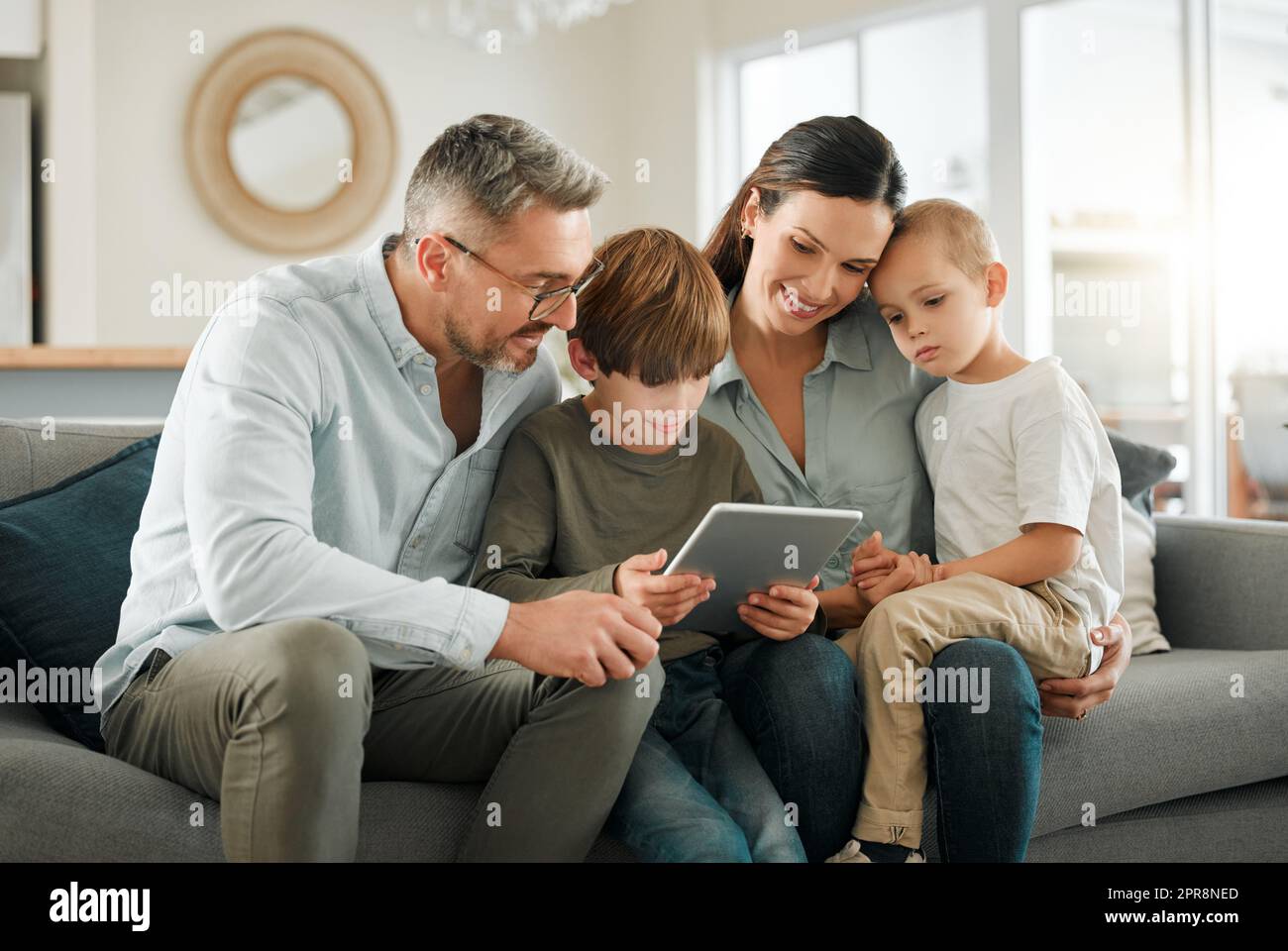 Ce que nous regardent aujourd'hui. Une famille utilisant une tablette numérique ensemble à la maison. Banque D'Images