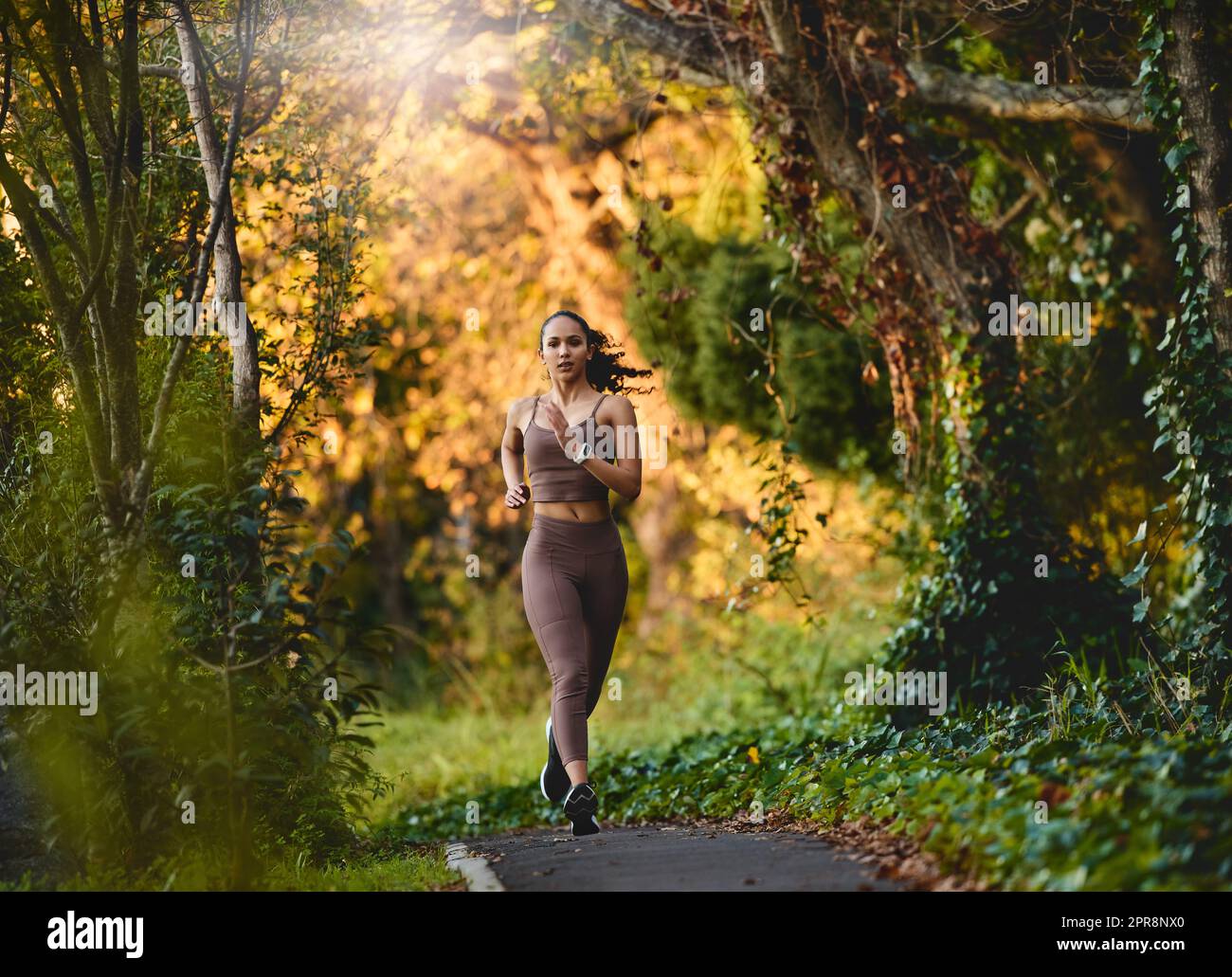 Elle profite de la beauté de la nature lors de sa course matinale. Une jeune femme sportive qui court à l'extérieur. Banque D'Images