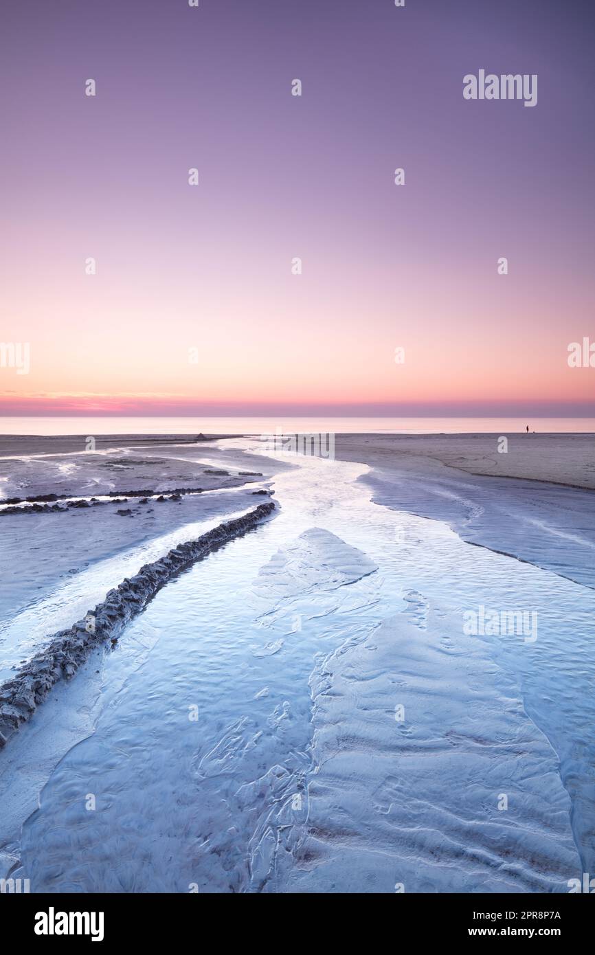 Vue sur le paysage d'un coucher de soleil dans un ciel rose sur la plage et la côte ouest de Jutland, Danemark. Un beau lever de soleil sur le bord de mer calme pour des vacances d'escapade et le tourisme. Paysage paisible au bord de l'océan Banque D'Images