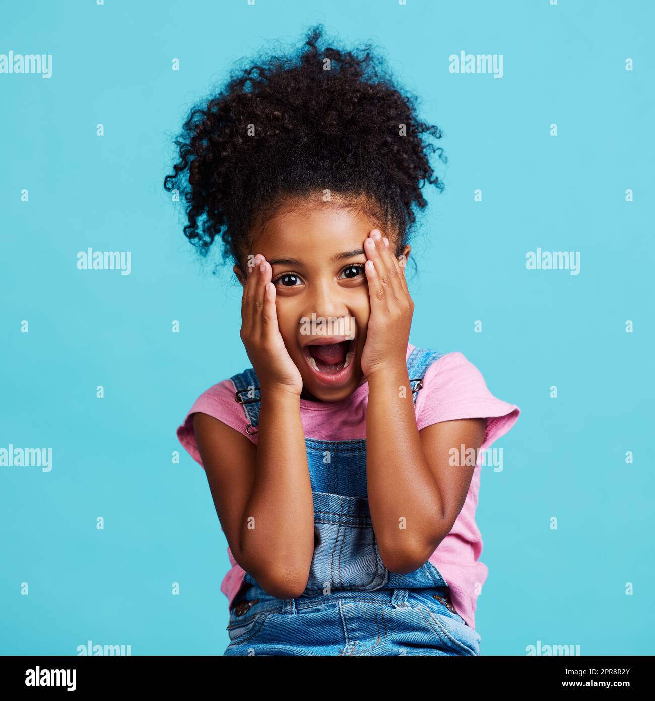 Je le perdante. Une petite fille regardant surpris tout en posant sur un fond bleu. Banque D'Images