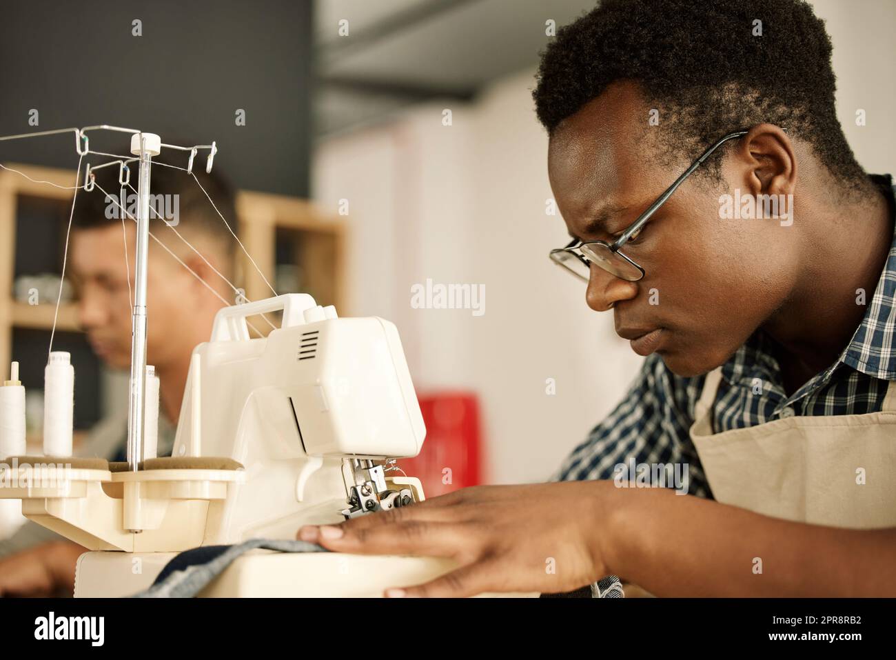 Tissu de couture de createur cible. Machine a coudre sur mesure. Un designer afro americain qui cousue un morceau de denim. Jeune homme d affaires travaillant sur une machine a coudre. Couture sur mes...
