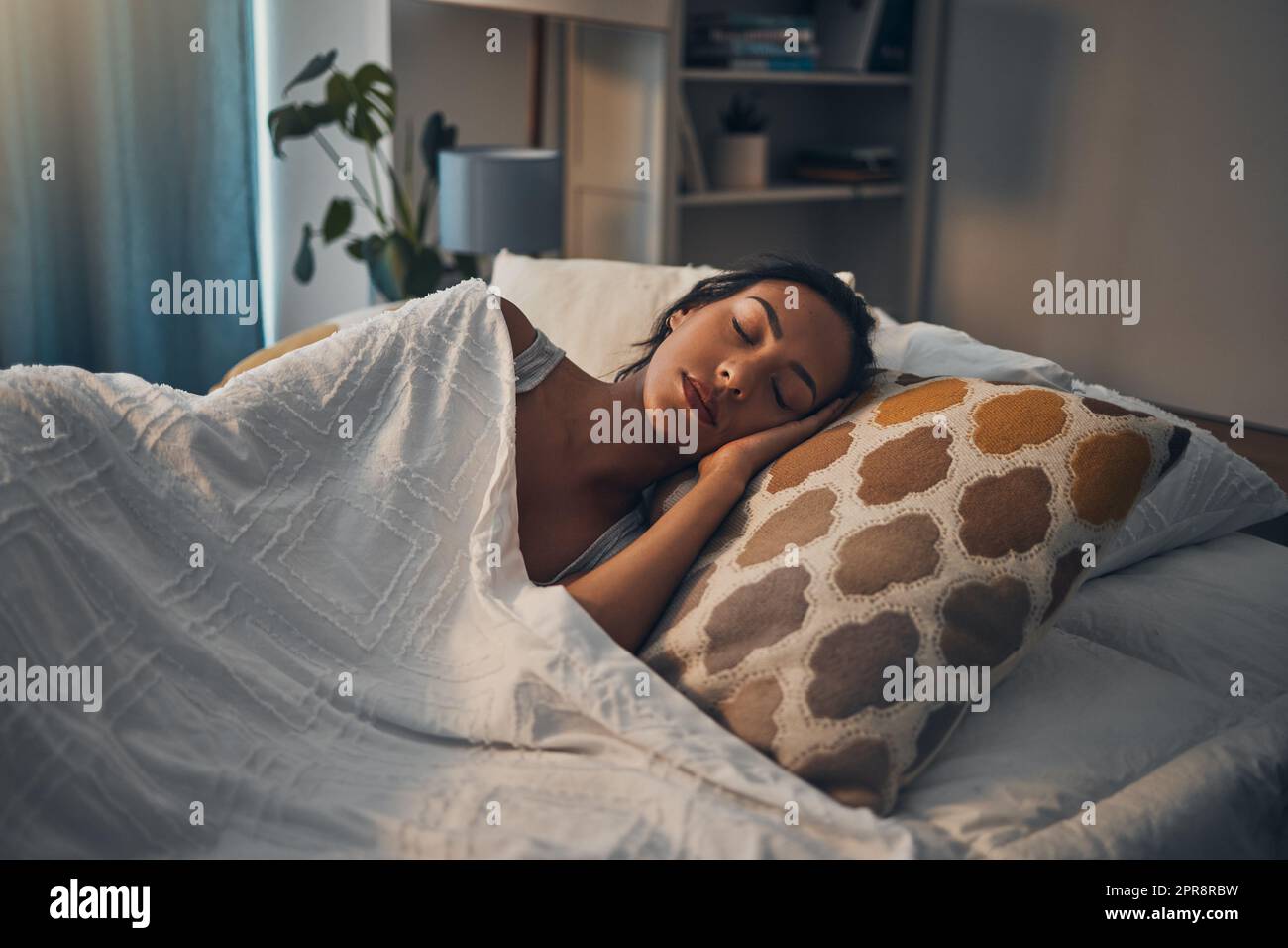 Une belle jeune femme mixte de race dormant dans un lit confortable et doux à la maison. Une femme hispanique se sentant épuisée et se reposant dans un lit réconfortant Banque D'Images