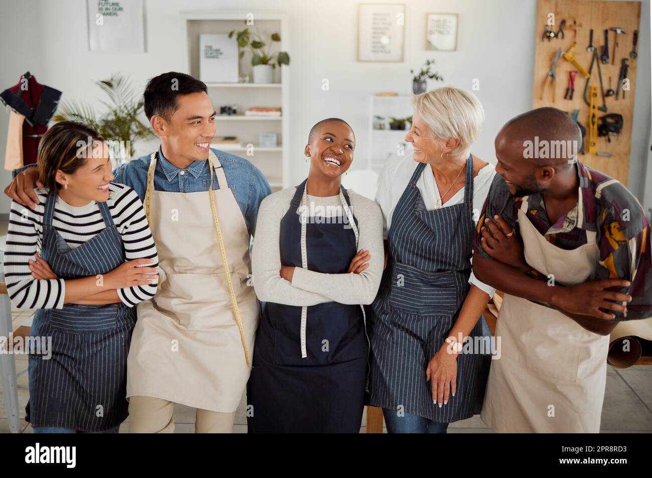 Groupe de cinq stylistes de vêtements divers et gais debout avec leurs bras croisés dans un magasin au travail. Il fait sourire et rire tout en se tenant ensemble dans une boutique Banque D'Images