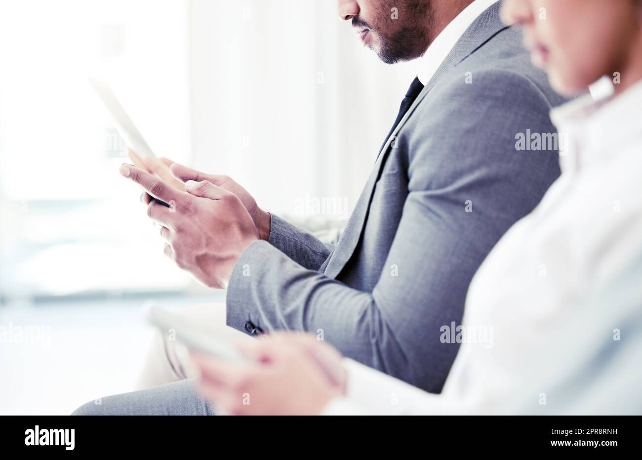 Un compagnon numérique pour vous aider à passer le temps. Gros plan d'un homme d'affaires méconnu utilisant une tablette numérique tout en étant assis dans la file d'attente dans un bureau. Banque D'Images