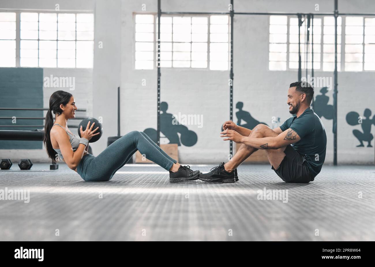 Un couple de fitness actif et sportif ou des partenaires de gym s'entraîner ensemble, faisant des exercices de base avec de l'équipement lourd. Entraîneur masculin et athlète féminin ayant une séance d'entraînement ou une classe amusante pour renforcer la force Banque D'Images