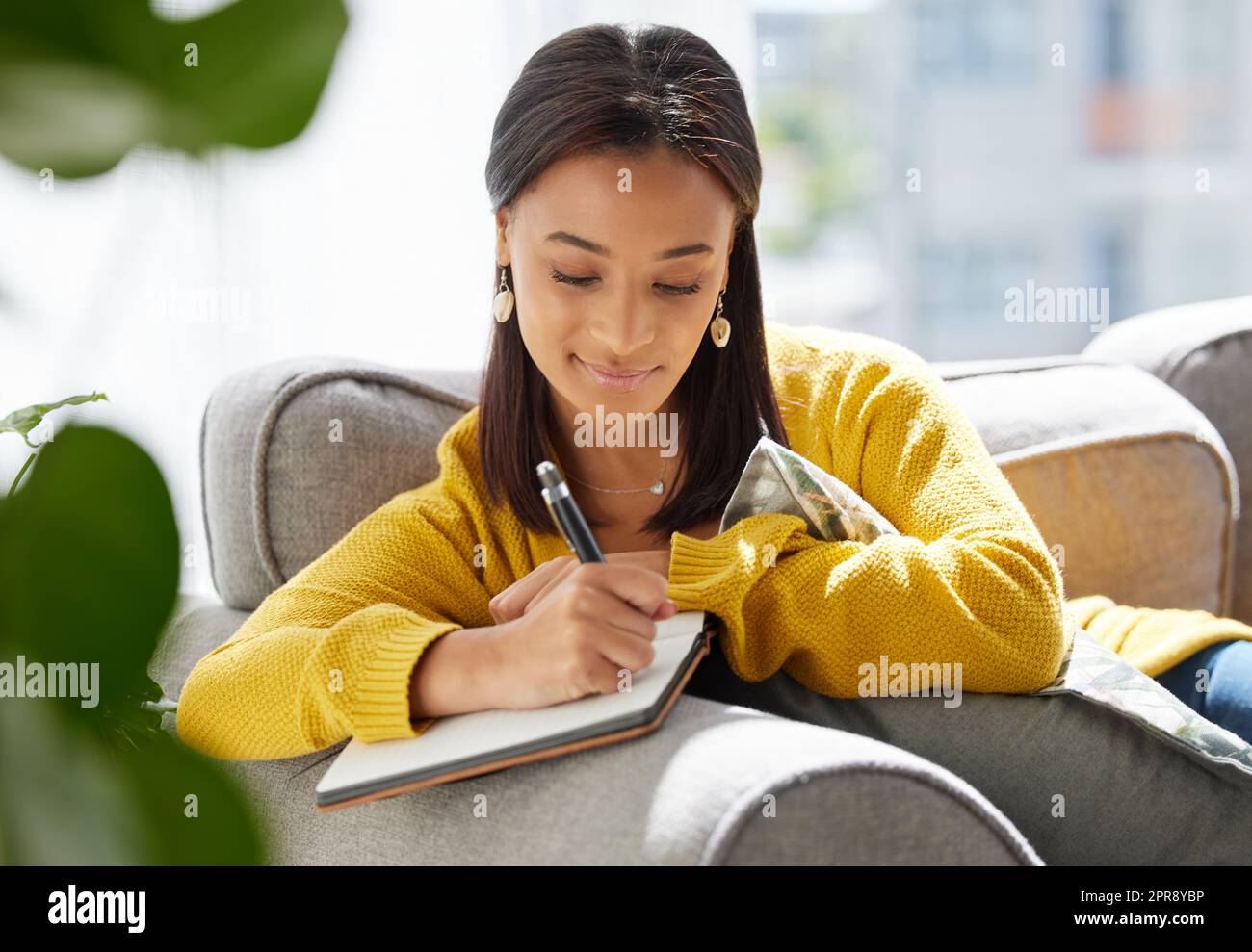 Pensées sur papier. Une jeune femme écrivant dans un journal à la maison. Banque D'Images