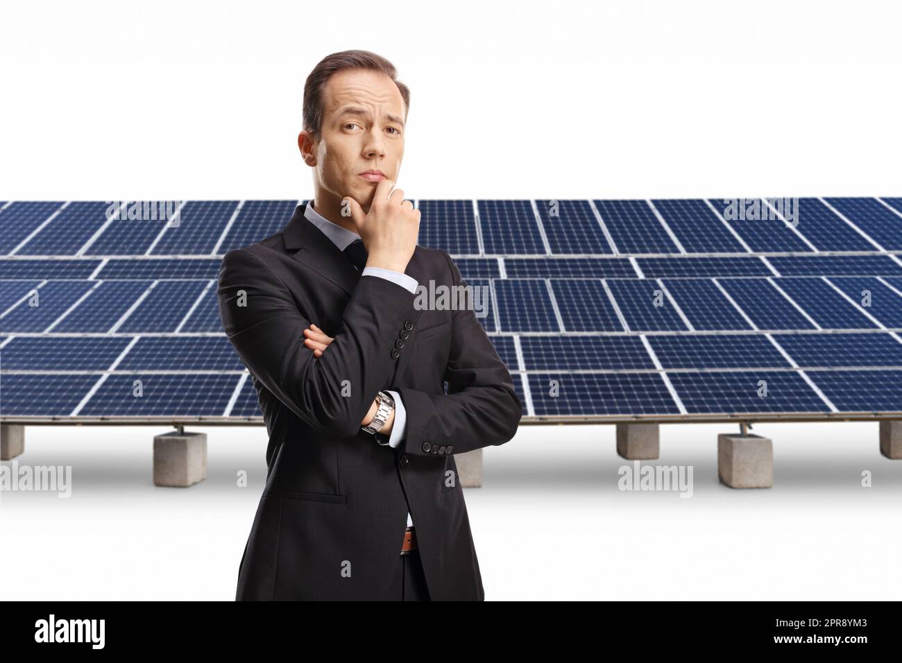 Homme d'affaires pensif tenant son menton devant des panneaux photovoltaïques isolés sur fond blanc Banque D'Images