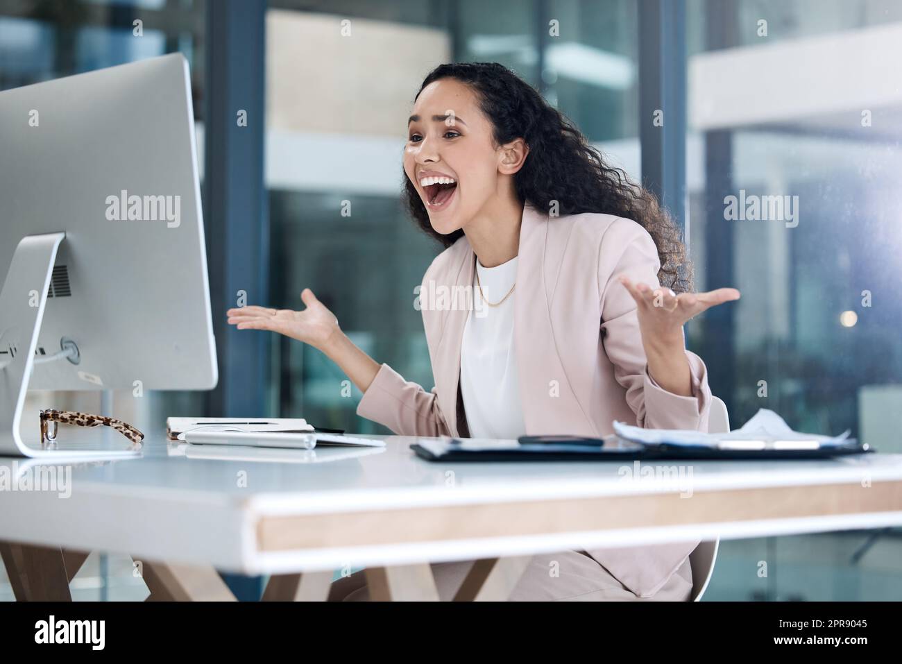 Jeune femme d'affaires heureuse de race mixte qui a l'air choqué et étonné d'utiliser un ordinateur de bureau dans un bureau. Un homme d'affaires hispanique joyeux souriant faisant un geste de main tout en regardant un écran de pc au travail Banque D'Images