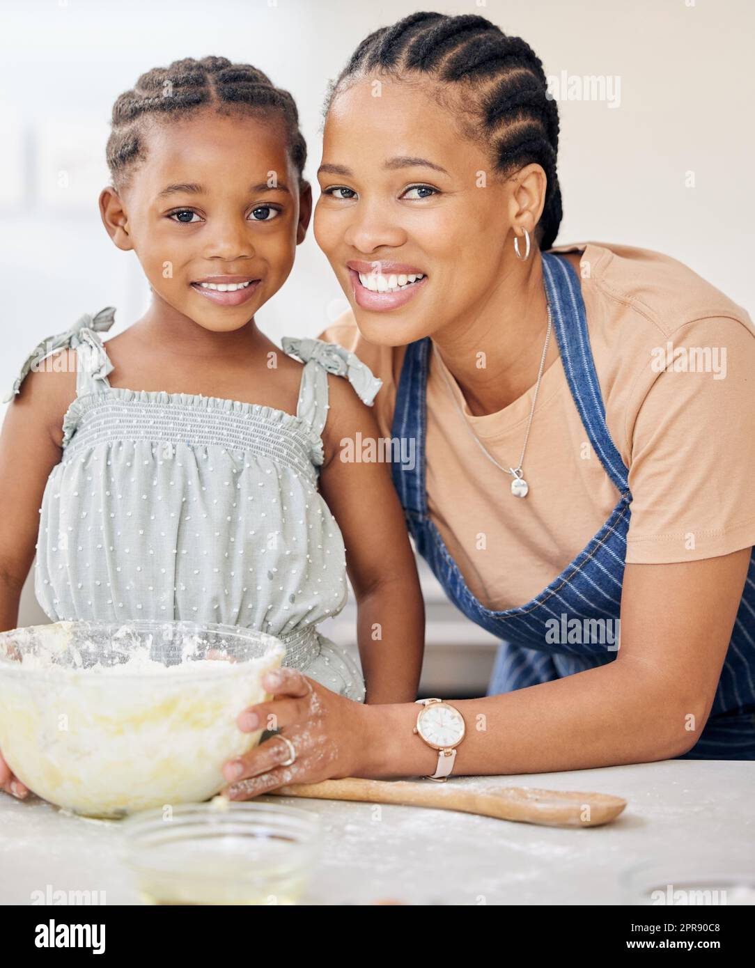 Mummys petite aide dans la cuisine. Une jeune mère attrayante liant avec sa fille et l'aidant à cuire dans la cuisine à la maison. Banque D'Images