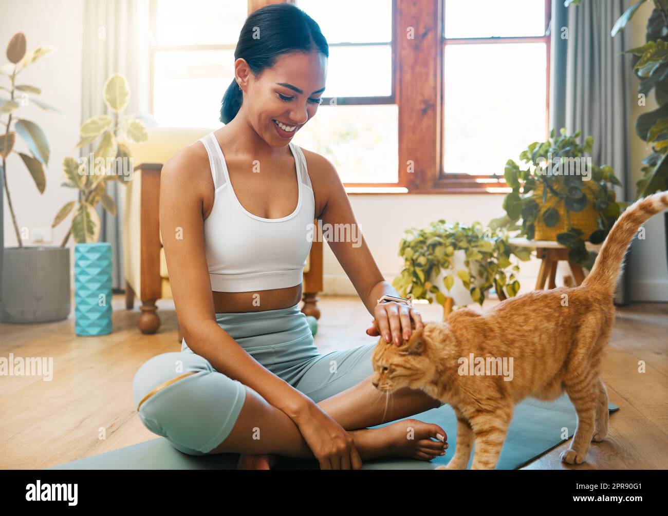 HES toujours exigeant mon attention. Une jeune femme sportive petting son chat tout en faisant de l'exercice à la maison. Banque D'Images