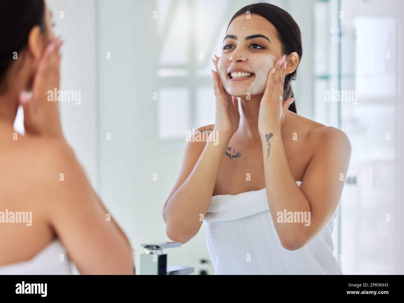 Nettoyer le visage en une étape. Une jeune femme lavant son visage dans une salle de bains à la maison. Banque D'Images