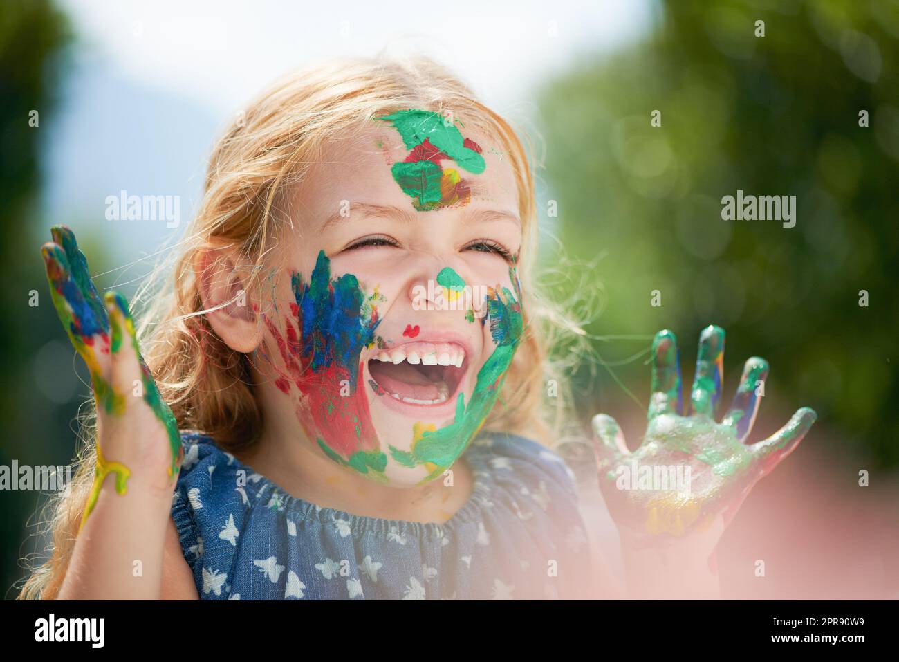 Obtenir salissant peut être la valeur. Une petite fille heureuse couverte de peinture. Banque D'Images