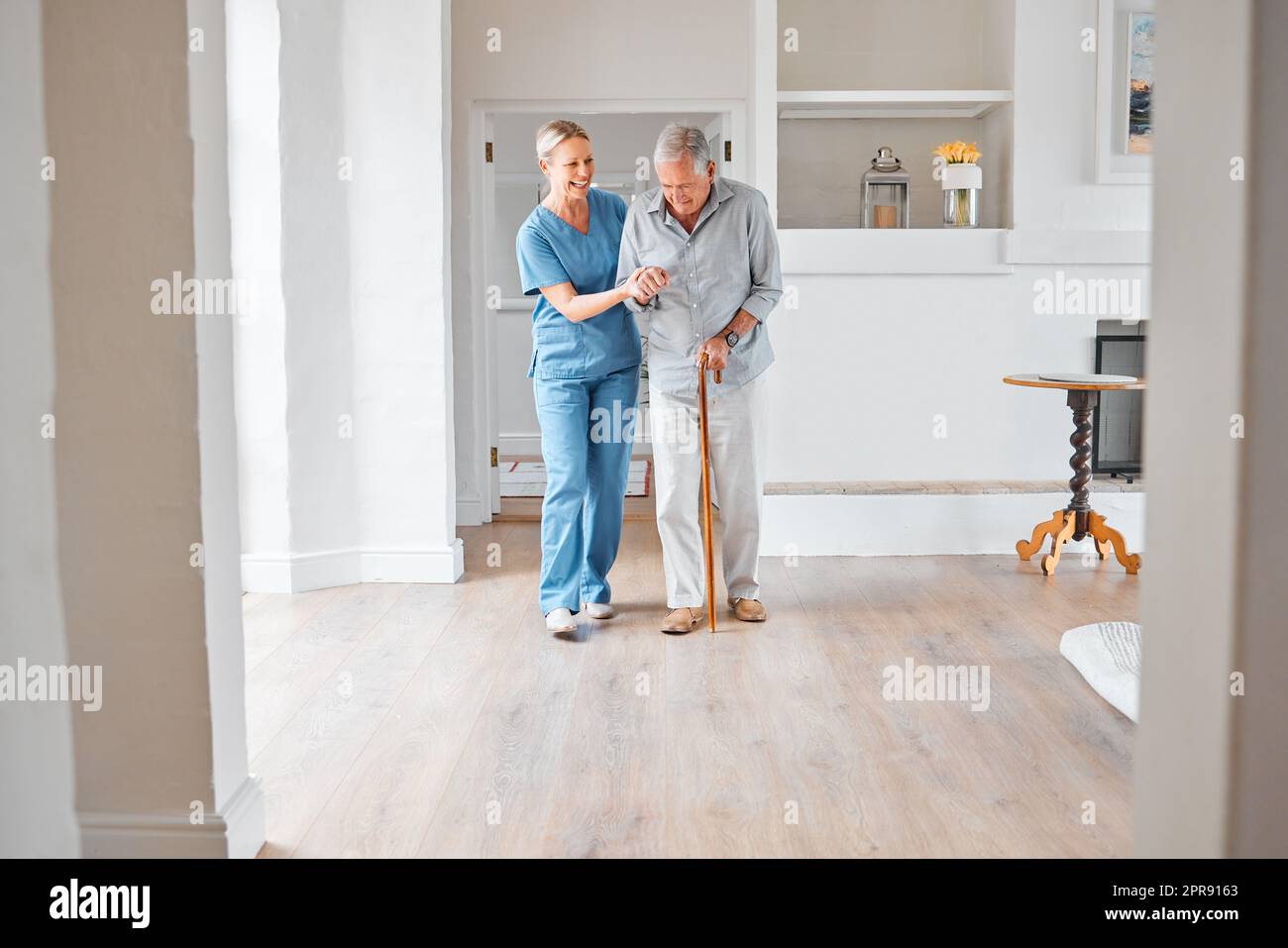 Je suis heureux de vous voir si plein d'énergie aujourd'hui. Une infirmière aide un homme âgé avec un bâton de marche dans une maison de retraite. Banque D'Images